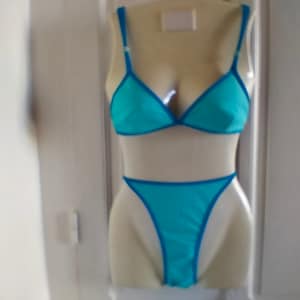 May include: A blue bikini set with a triangle top and a thong bottom. The bikini is on a white mannequin.