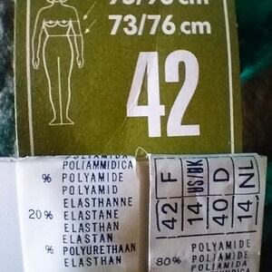 May include: A white tag with black text showing size information for a garment. The tag includes the size 42, the measurements 95/98 cm and 73/76 cm, and the fabric composition: 80% polyamide and 20% elastane.