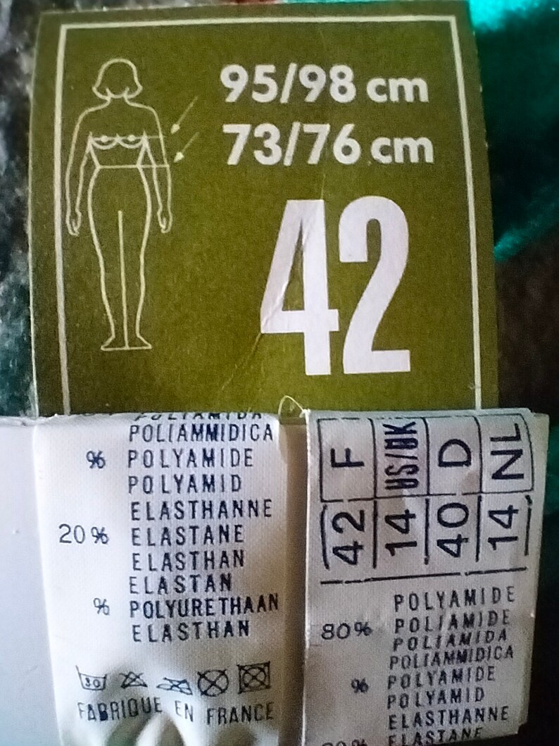 May include: A white tag with black text showing size information for a garment. The tag includes the size 42, the measurements 95/98 cm and 73/76 cm, and the fabric composition: 80% polyamide and 20% elastane.