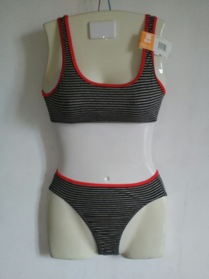 May include: Black and white striped underwear set with red trim. The top is a sports bra style with thin straps. The bottom is a bikini style with a low rise.