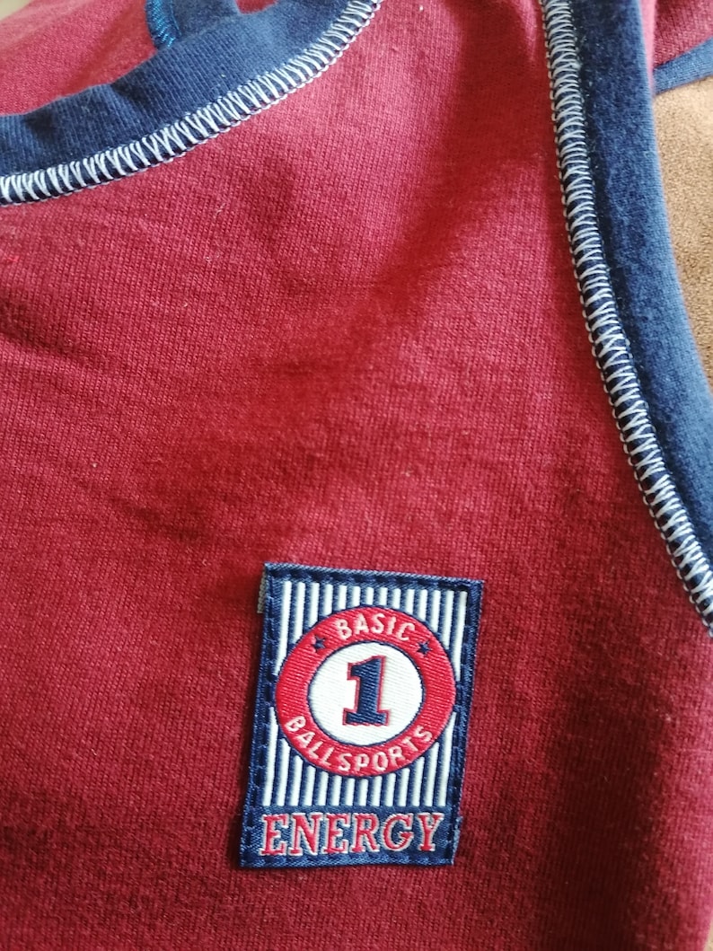 May include: Red shirt with a blue and white striped patch that says "BASIC BALL SPORTS ENERGY" with a red circle and the number "1" in white.
