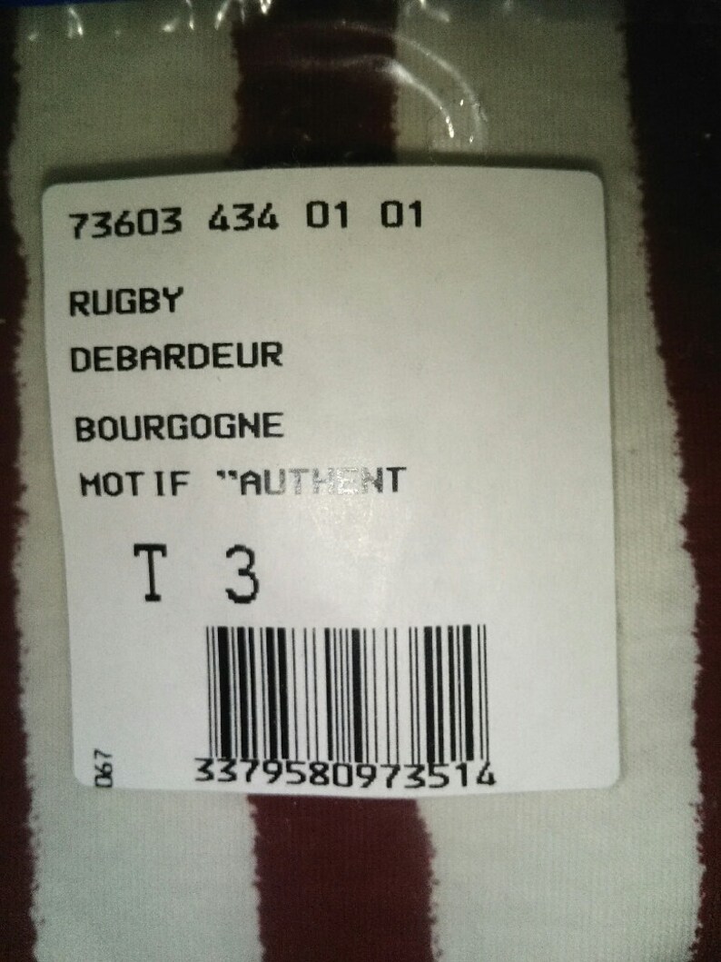 May include: White and burgundy striped fabric with a white tag attached. The tag has the text "73603 434 01 01", "RUGBY", "DEBARDEUR", "BOURGOGNE", "MOT IF "AUTHENT", "T 3" and a barcode with the number "3379580973514".