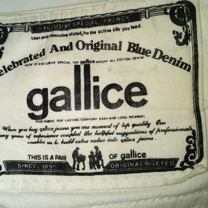 May include: A white label with black text that reads "Celebrated And Original Blue Denim" and "gallice". The label also includes the text "Exclusive Special French", "Made of Exclusive Special Top gallice Weight All Cotton Denim", "This Fabric for Lasting Comfort Easy and Long Wearing", "When you buy gallice jeans you are assured of top quality", "This is a Pair", "Since 1895", "Of gallice", and "Original Riveted".