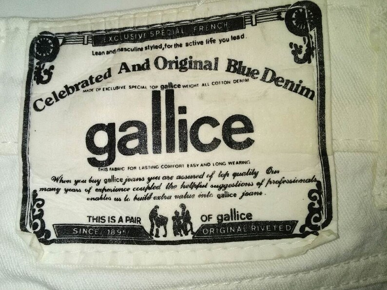 May include: A white label with black text that reads "Celebrated And Original Blue Denim" and "gallice". The label also includes the text "Exclusive Special French", "Made of Exclusive Special Top gallice Weight All Cotton Denim", "This Fabric for Lasting Comfort Easy and Long Wearing", "When you buy gallice jeans you are assured of top quality", "This is a Pair", "Since 1895", "Of gallice", and "Original Riveted".