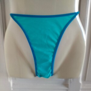 May include: Light blue lingerie with a turquoise trim. The lingerie is made of a sheer fabric and has a low-cut back.