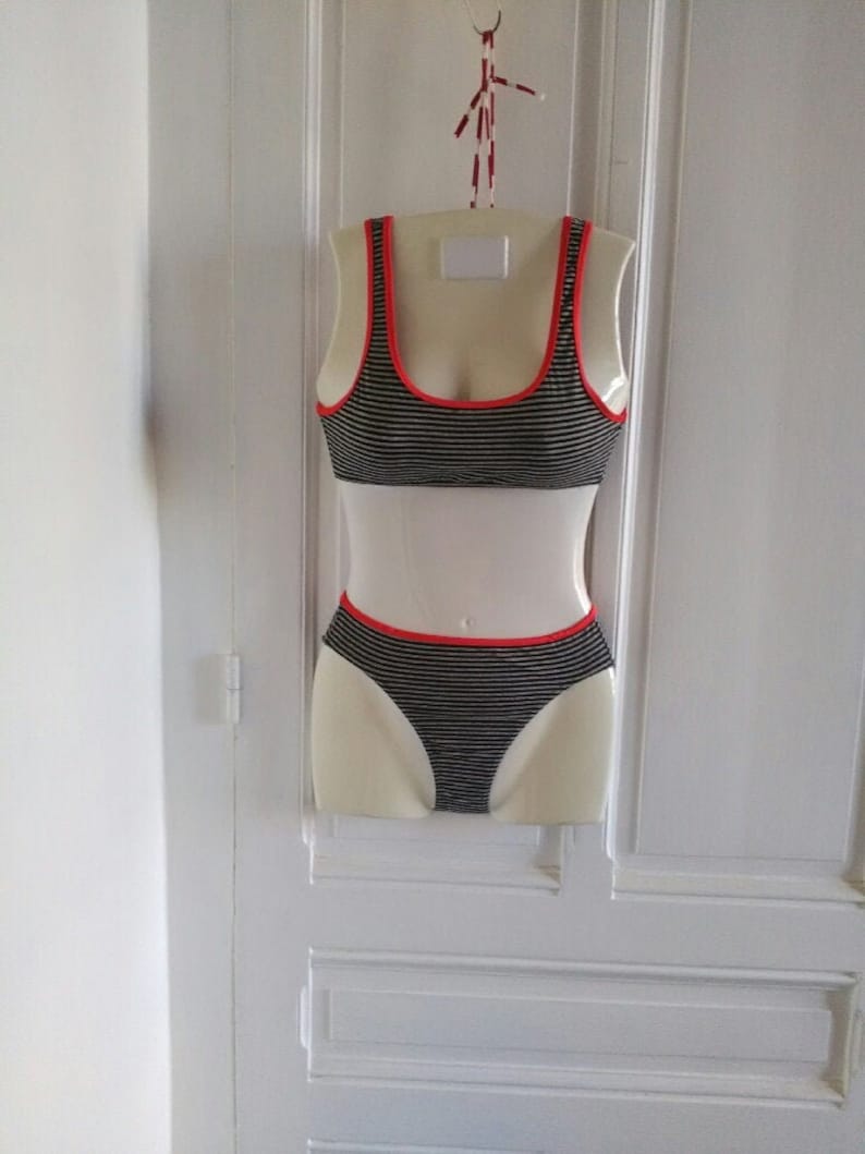 May include: Black and white striped bikini top and bottom with red trim. The bikini is displayed on a white mannequin.