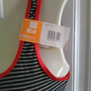 May include: A black and white striped tank top with red trim. The tank top has a tag that says "12 ans" and a barcode.