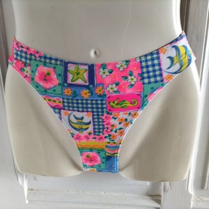 Puede incluir: Braguita de bikini colorida con un dise&ntilde;o de patchwork. La tela presenta motivos florales, de criaturas marinas y geom&eacute;tricos en tonos rosa, azul, verde y amarillo. La braguita de bikini se muestra en un maniqu&iacute;.