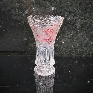 Könnte beinhalten: Eine klare Glasvase mit einem roten Drachenmotiv. Die Vase hat einen gewellten Rand und eine strukturierte Oberfläche.