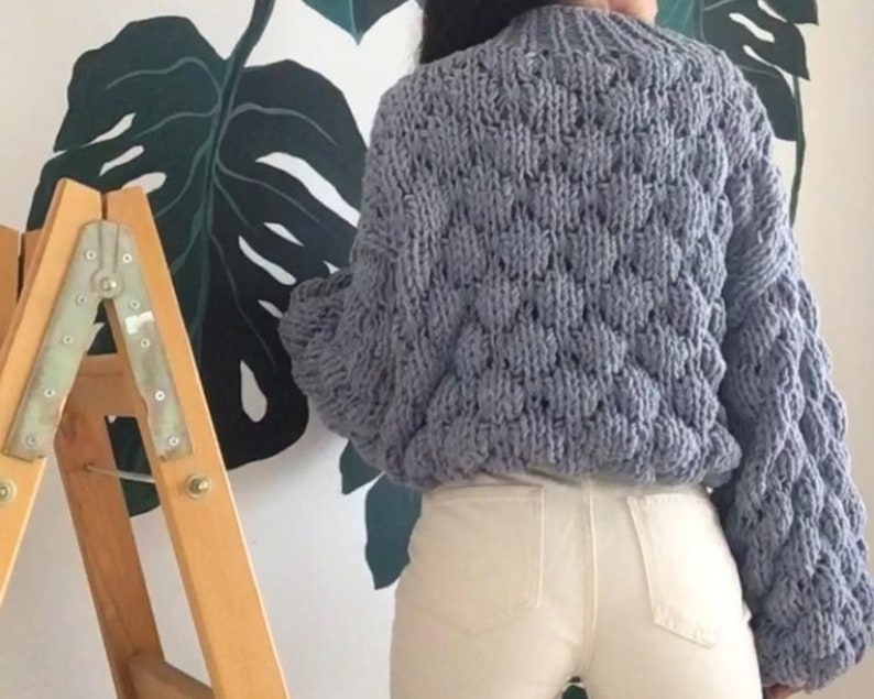 Pu&ograve; includere: Un maglione di lana grossa di colore azzurro chiaro con un motivo testurizzato. Il maglione ha maniche lunghe e una vestibilit&agrave; comoda.