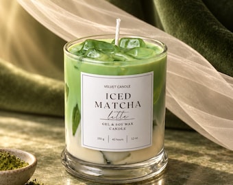 Pode incluir: Uma vela em copo de vidro transparente com camadas de cera verde e branca que lembram um matcha latte gelado, com cubos de cera verde e um pavio branco. O rótulo diz VELVET CANDLE ICED MATCHA latte GEL & SOY WAX CANDLE 250 g 40 hours 12 oz.