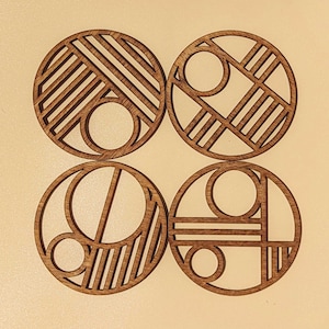 May include: Set of four wooden coasters with geometric designs. Each coaster features a different pattern of circles, lines, and stripes.
