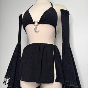 May include: Black glittery two-piece outfit with a halter top and skirt. The top features a silver crescent moon charm, and the skirt has side slits. The outfit includes matching arm sleeves and leg garters with star accents.