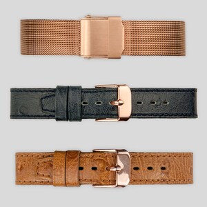 May include: Three watch straps in different styles: a rose gold metal mesh strap, a dark blue leather strap, and a brown leather strap with a textured pattern.