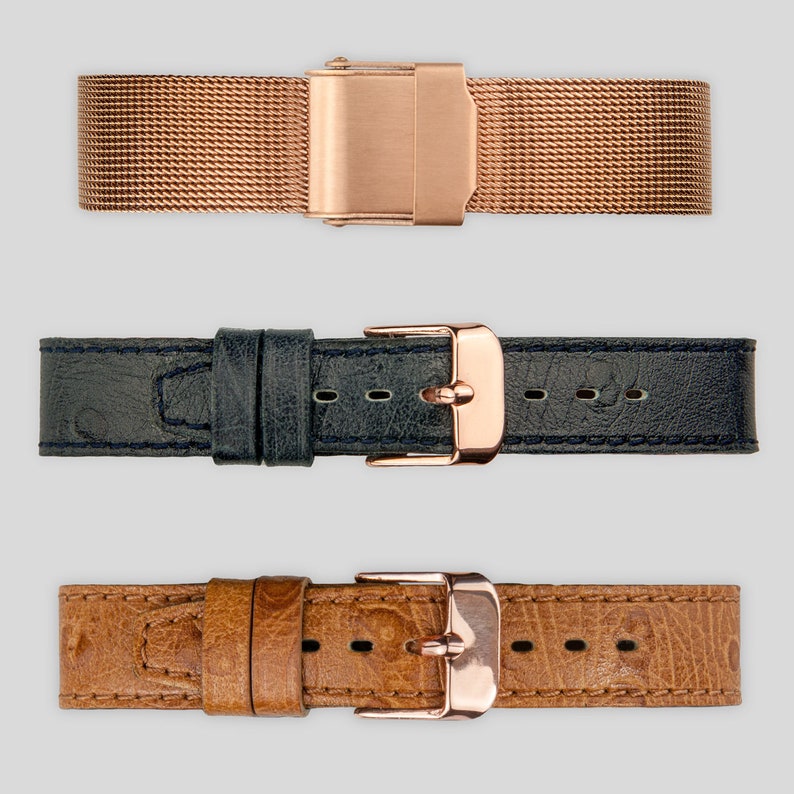 May include: Three watch straps in different styles: a rose gold metal mesh strap, a dark blue leather strap, and a brown leather strap with a textured pattern.