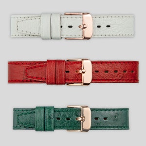 May include: Three leather watch straps with rose gold buckles. The straps are white, red, and green.