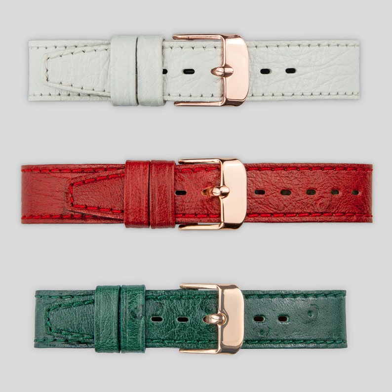 May include: Three leather watch straps with rose gold buckles. The straps are white, red, and green.