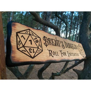 May include: A wooden sign with a burnt edge, featuring a 20-sided die and the text "Brent's Dungeon Roll For Initiative".