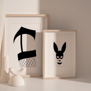 May include: Two framed black and white illustrations. The first illustration is of a black silhouette of a leg wearing a fishnet stocking. The second illustration is of a black silhouette of a bunny mask.