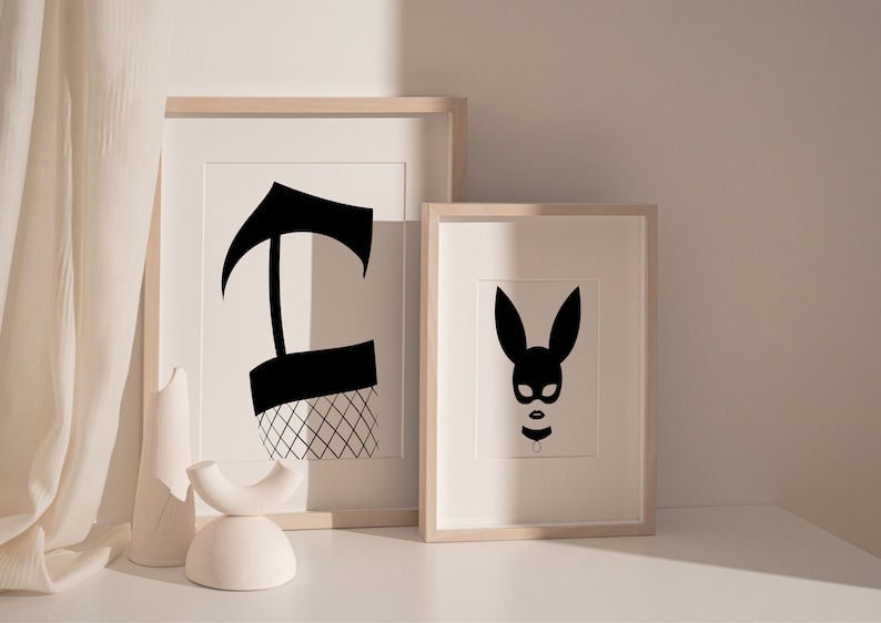 May include: Two framed black and white illustrations. The first illustration is of a black silhouette of a leg wearing a fishnet stocking. The second illustration is of a black silhouette of a bunny mask.