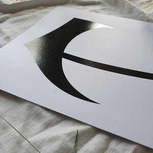 May include: A black and white print of a stylized letter E on a white background.