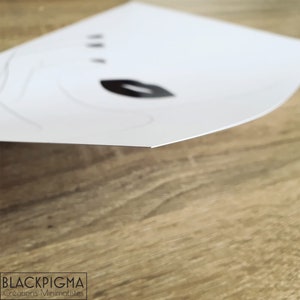 May include: A white card with black ink printed on it. The card has a simple design with a leaf and three dots. The text "BLACK PIGMA Creations Minimalistes" is printed at the bottom of the card.