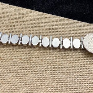 May include: Silver bracelet with oval-shaped white mother-of-pearl links. The bracelet has a clasp and a tag that says "925".