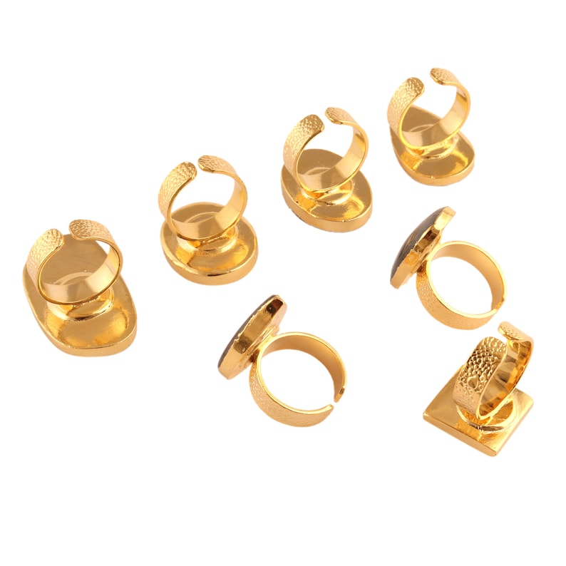 Puede incluir: Ocho soportes de exhibici&oacute;n de anillos de tono dorado con bases ovaladas. Cada soporte tiene un soporte para anillos y una piedra negra en el centro.