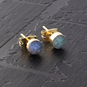 Op de afbeelding: Een paar gouden oorbel studs met iriserende blauwe labradorite edelstenen.