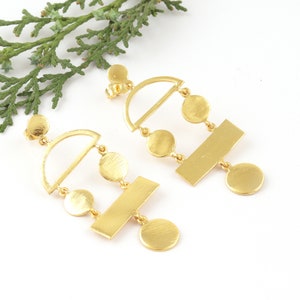 May include: Gold geometric dangle earrings with multiple circles and a bar design.