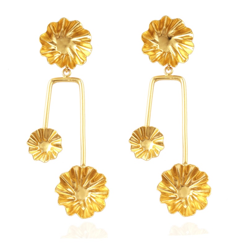 May include: Gold tone earrings with three flower-shaped charms on each earring. The charms are connected by a thin metal bar.