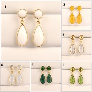 May include: Ten pairs of gold drop earrings with different colored gemstones. The earrings feature a small round gemstone at the top and a larger teardrop-shaped gemstone hanging below. The gemstones are white, yellow, clear, and green.