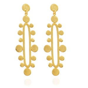 May include: A pair of gold-toned dangle earrings with a geometric design. The earrings feature a series of small circles arranged in a vertical pattern.