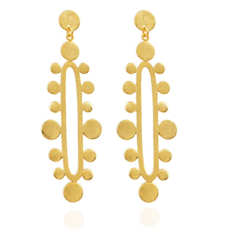 May include: A pair of gold-toned dangle earrings with a geometric design. The earrings feature a series of small circles arranged in a vertical pattern.