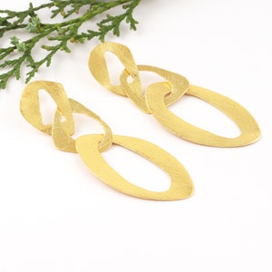May include: Gold-toned dangle earrings with a chain-link design. Each earring features three oval-shaped links.