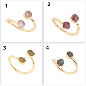Könnte beinhalten: Vier goldene Ringe mit verschiedenen farbigen Edelsteinen. Jeder Ring hat zwei Steine, einen auf jeder Seite des Bandes. Die Ringe haben alle den gleichen Stil, mit einem einfachen, geschwungenen Band.
