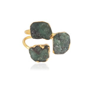 Peut inclure: Bague en or avec trois pierres vert émeraude. Les pierres sont de forme irrégulière et ont un aspect brut et naturel.