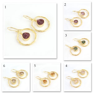 May include: Six pairs of gold hoop earrings with different coloured gemstones. Each pair features a single gemstone dangling from a gold hoop.