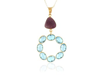 May include: A gold necklace with a pendant featuring a purple gemstone and a circle of light blue gemstones.