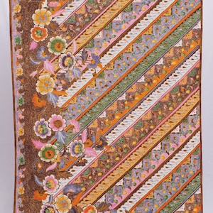 May include: A rectangular textile with a brown border and a vibrant floral and geometric pattern. The design features diagonal stripes in shades of brown, orange, pink, green, and blue, with detailed floral motifs along the edges.