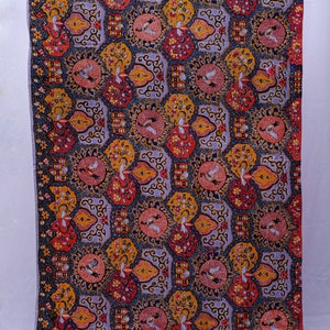 May include: A rectangular textile with a repeating pattern of circular and floral designs. The fabric features a colour palette of red, yellow, pink, and blue on a lavender background. The design includes bird motifs and ornate shapes.