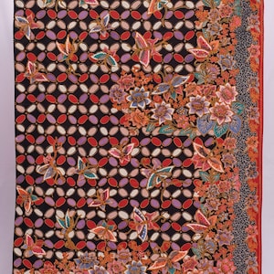 以下が含まれることがあります： 赤、紫、白の楕円が繰り返される模様の黒いテキスタイル。オレンジ、青、ピンクの色合いの蝶と花の模様が生地全体に散りばめられています。赤い縁が端を縁取っています。