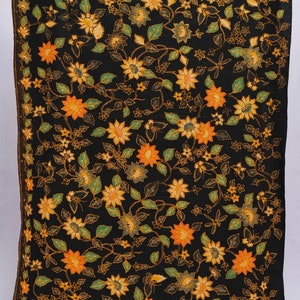 May include: Black textile with a floral pattern featuring orange and yellow flowers, green leaves, and delicate vines. The design is repeated across the fabric, creating a visually rich and detailed pattern. The edges are finished with a decorative border.