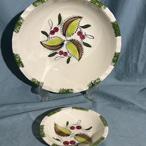 May include: A set of two white ceramic bowls with green and brown leaf designs and red berries. The larger bowl is 25 cm in diameter and the smaller bowl is 15 cm in diameter.
