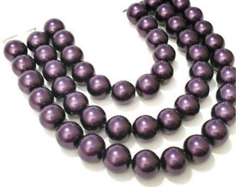 May include: A triple strand necklace made of dark purple faux pearls.