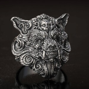 May include: A detailed silver ring featuring a wolf's head design. The ring showcases intricate carvings, including a snarling mouth, pointed ears, and swirling patterns. The ring is a statement piece, perfect for those who appreciate unique jewelry.