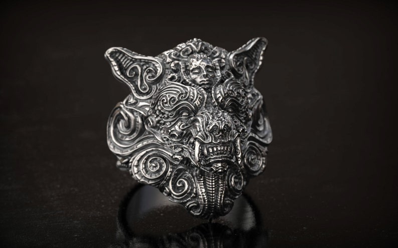 May include: A detailed silver ring featuring a wolf's head design. The ring showcases intricate carvings, including a snarling mouth, pointed ears, and swirling patterns. The ring is a statement piece, perfect for those who appreciate unique jewelry.