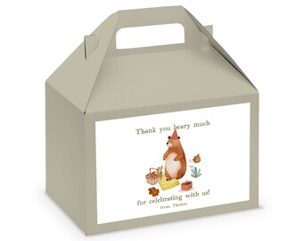 May include: A light brown favor box with a handle. The box has a white label with a cartoon bear wearing a party hat and holding a basket. The text on the label reads "Thank you bear-y much for celebrating with us!" and "From, Thomas".