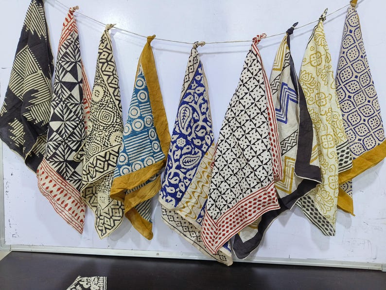 May include: Eight different fabric squares with black and white geometric patterns, some with a yellow border, some with a red border, and one with a blue border.