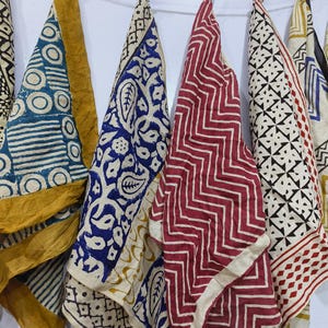 May include: Five fabric squares with different patterns and colors, including blue, red, yellow, and white. The squares are hanging on a string.